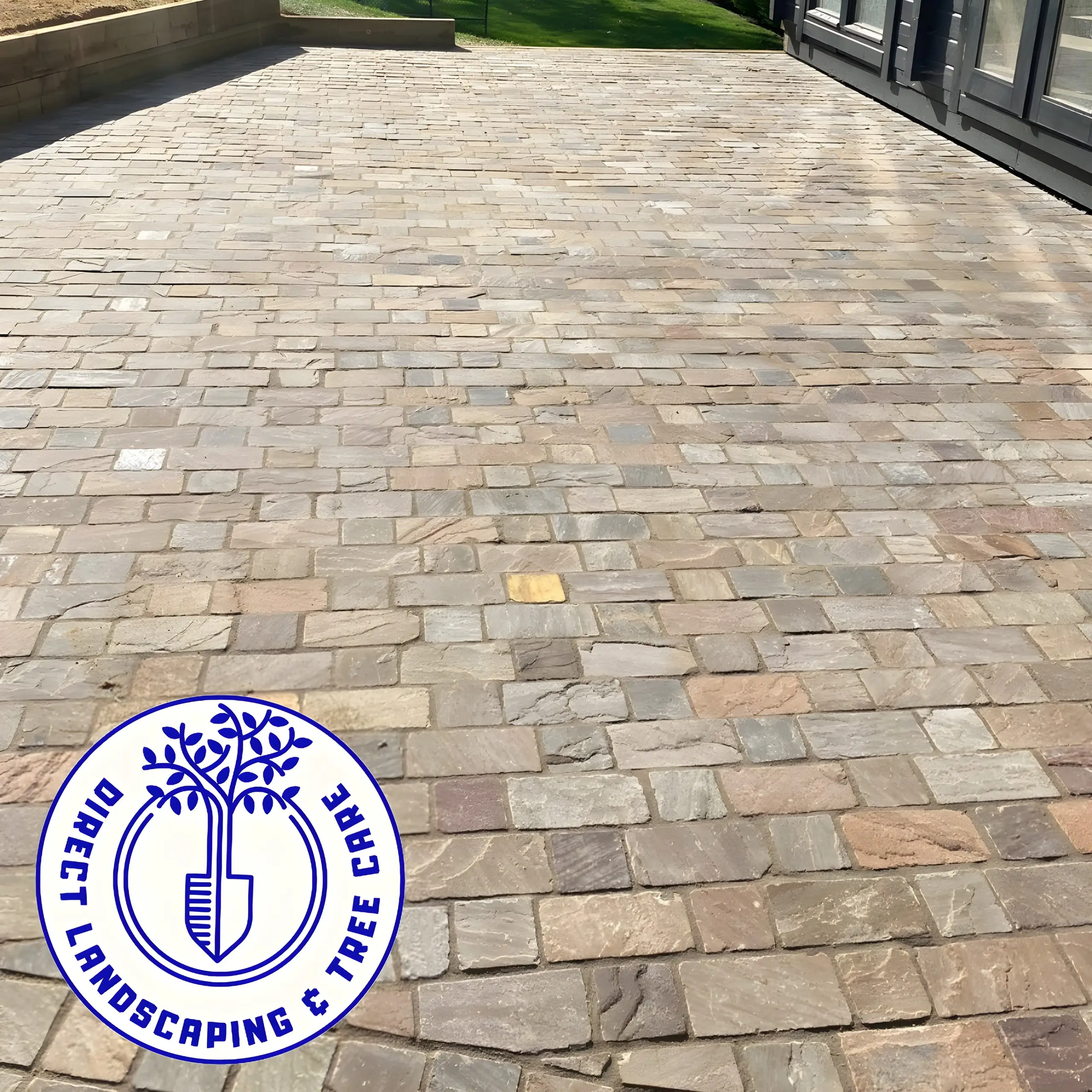 Driveway laid in tumbled block paving setts running up to a house