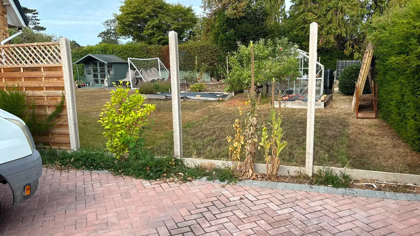 Completed block paved driveway with new fence posts and a garden beyond