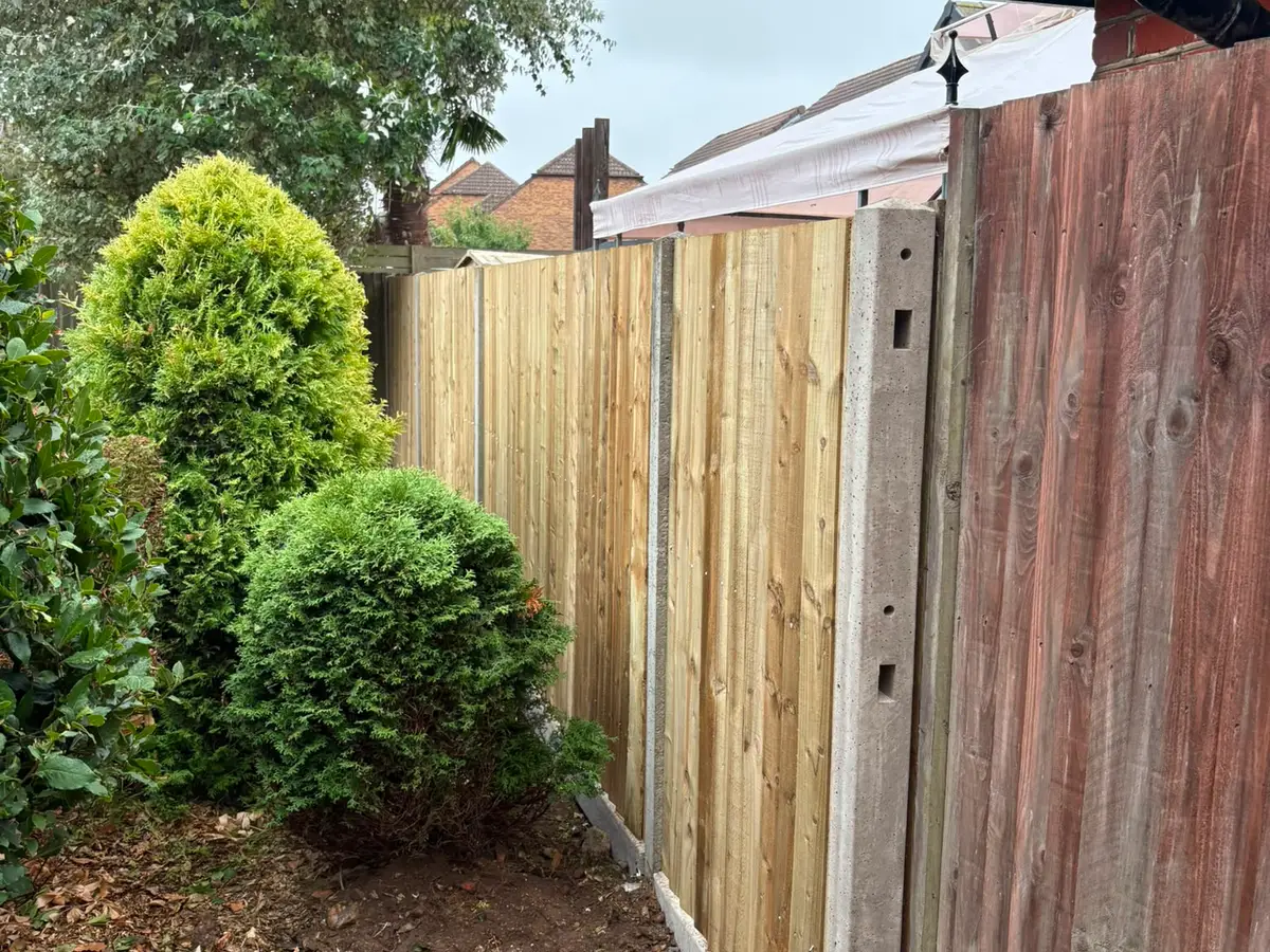 A newly built closeboard fence standing next to the weathered old fence it replaces