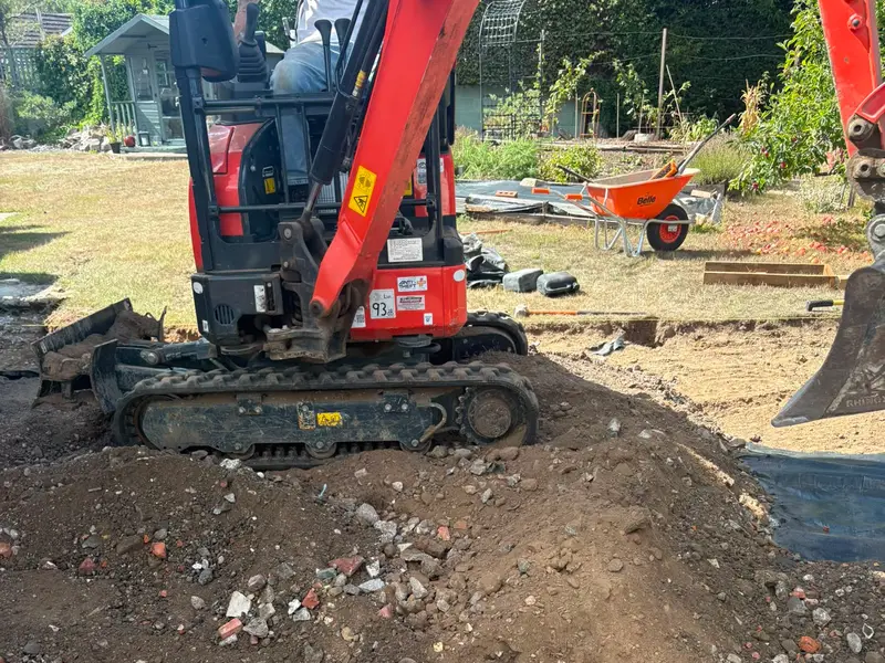 Mini digger excavating the old surface out beside the existing paving